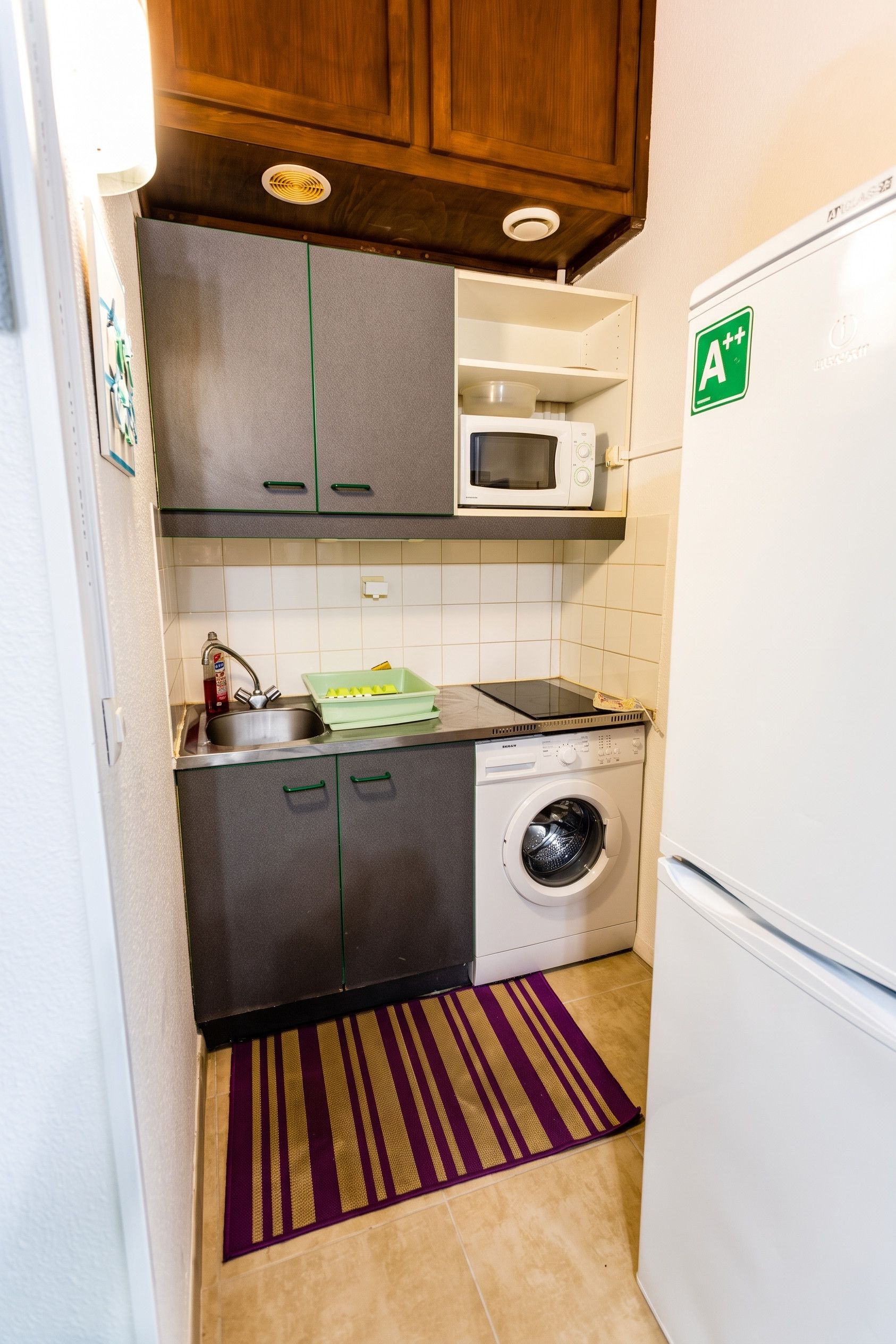 Una cocina compacta con microondas, lavadora y refrigerador.