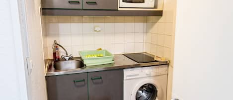 Una cocina compacta con microondas, lavadora y refrigerador.