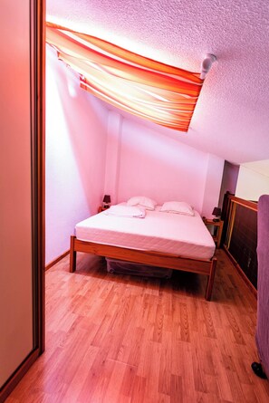 A small, cozy bedroom with a wooden bed, a nightstand, and a wall-mounted lamp. - Homerez - House in Argelès-sur-Mer with shared pool (Argelès-sur-Mer)
