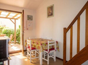A dining area with a table and chairs, a wooden staircase, and a door leading to an outdoor space.