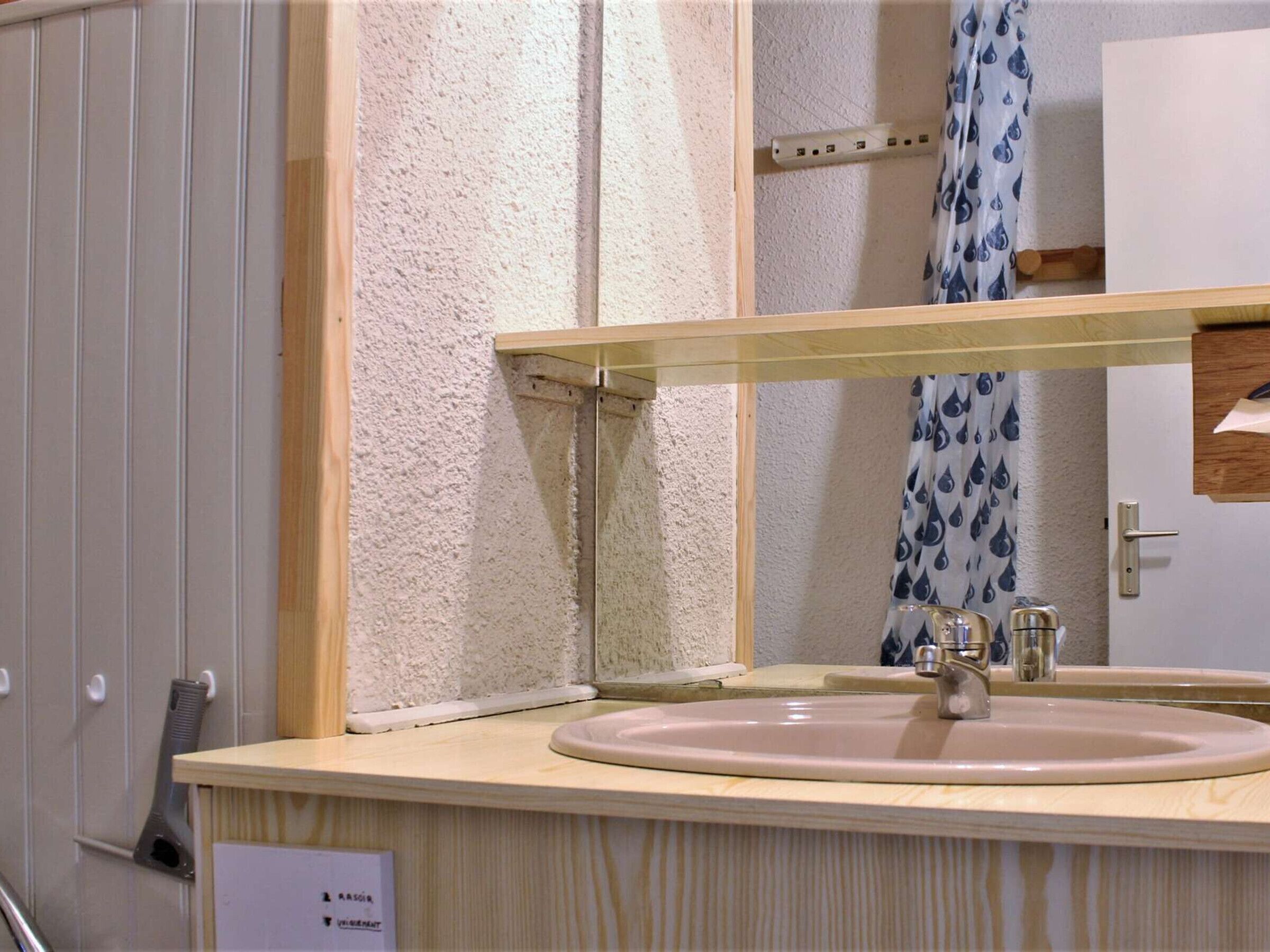 A bathroom with a white sink, a mirror, and a shower curtain with a water droplet pattern.