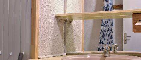 A bathroom with a white sink, a mirror, and a shower curtain with a water droplet pattern.