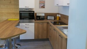 Una cocina compacta con encimera de madera, horno integrado, cafetera y tostadora.
