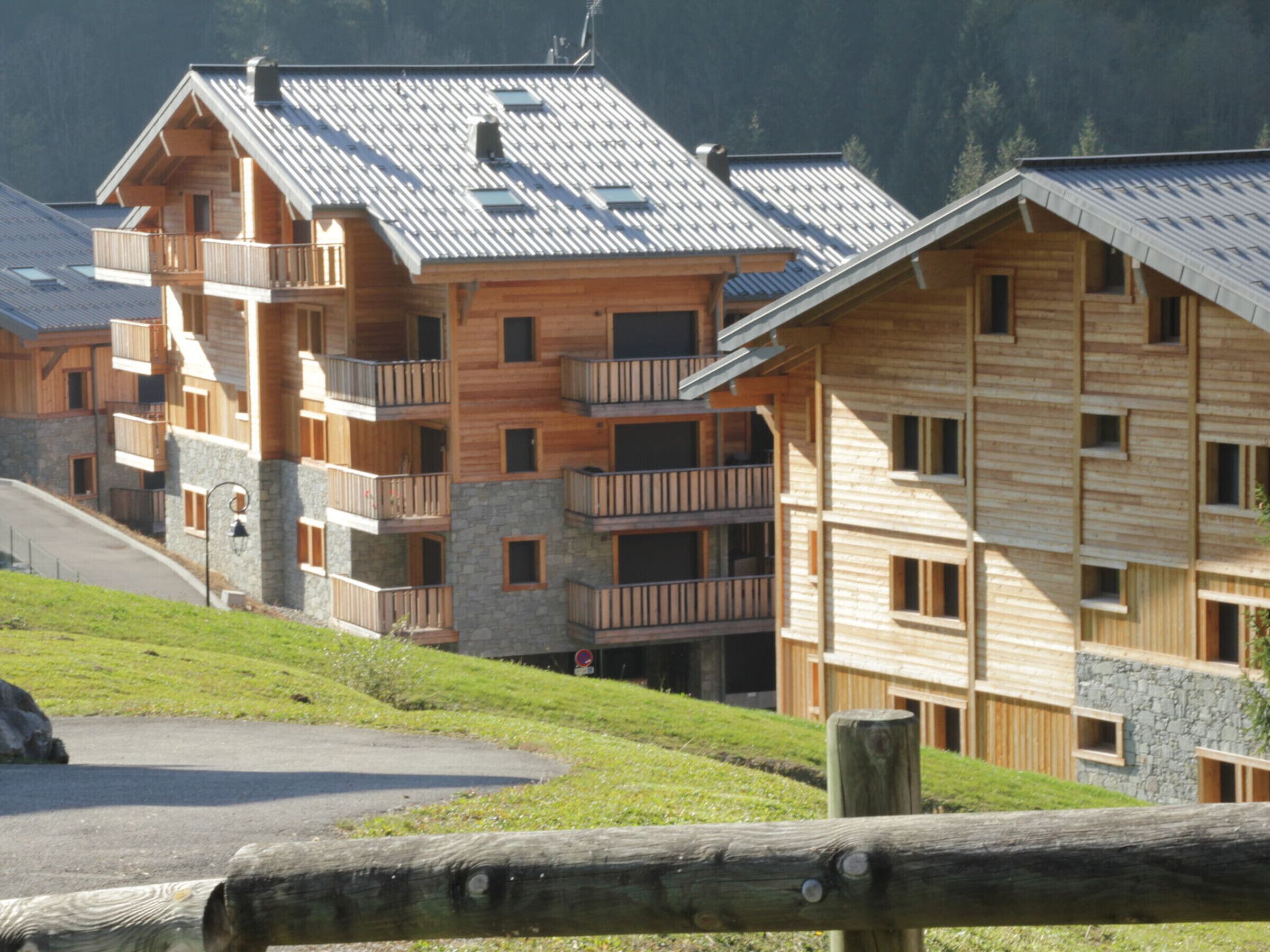 A multi-story wooden building with balconies, set in a hilly area.