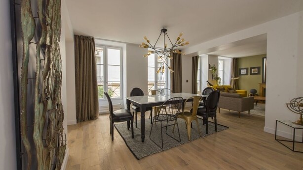 A modern dining area with a wooden table, chairs, and a chandelier. - Balthazar, 4BR/4BA, 9 people (París)