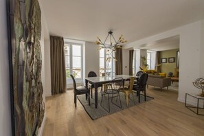 A modern dining area with a wooden table, chairs, and a chandelier. - Balthazar, 4BR/4BA, 9 people (París)
