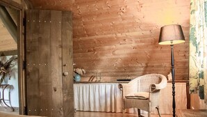 A rustic wooden room with a bed, a wicker chair, a table with a lamp, and a wooden wardrobe. - Charming eco-gîte, no TV or internet, pets welcome (La Mouche)