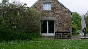 A stone house with a gabled roof, a front door, and a small porch area with outdoor seating. - Charming eco-gîte, no TV or internet, pets welcome (La Mouche)