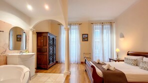 A bedroom with a large bed, a wooden wardrobe, a vanity with a mirror, and a bathtub. - N&J - MEYERBEER - Central - Very close sea (Niza)