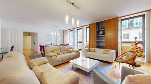 Una sala de estar moderna con dos sofás, una mesa de centro y un comedor con sillas.