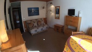 Una sala acogedora con un sofá, una mesita, un mueble para televisión y una mesa de comedor.