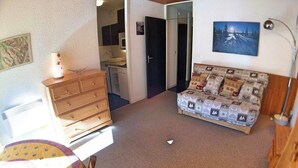Un dormitorio con un aparador de madera, un sofá estampado, una cama y un cuadro en la pared.