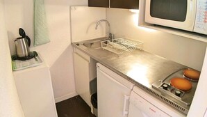 Una kitchenette compacta con un lavamanos de acero inoxidable, un microondas, un lavavajillas Bosch y una cafetera pequeña.
