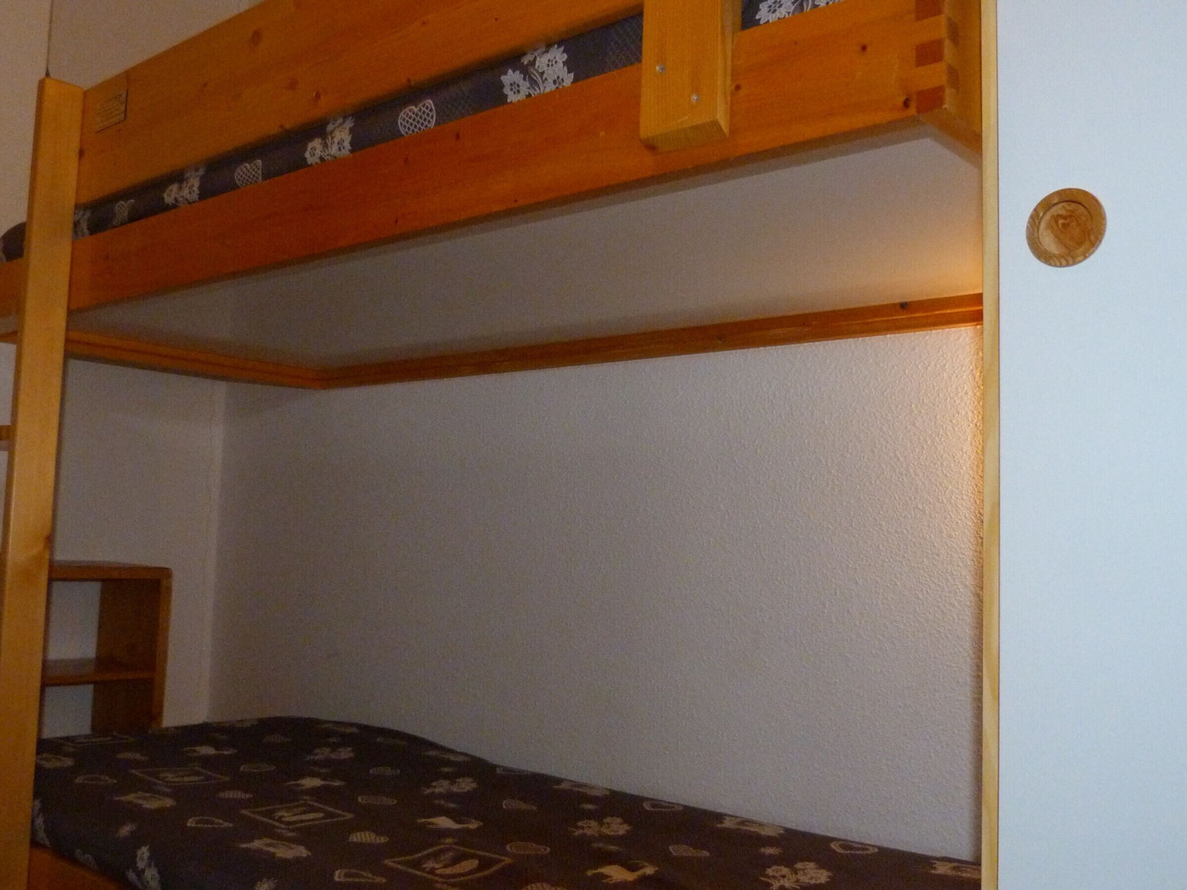 A bunk bed with a wooden frame and a patterned bedspread.