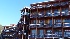 A multi-story hotel with balconies and a ski rental sign. - 2-room duplex, sleeps 6, ski-in/ski-out, Charmettoger (Les Arcs 1800)
