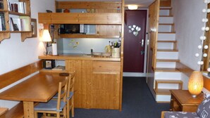 A compact kitchen with wooden cabinets, a dining table with chairs, a refrigerator, and a microwave. - 2-room duplex, sleeps 6, ski-in/ski-out, Charmettoger (Les Arcs 1800)