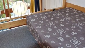 A bedroom with a bed, a window with blinds, and a view of trees and a building outside. - 2-room duplex, sleeps 6, ski-in/ski-out, Charmettoger (Les Arcs 1800)