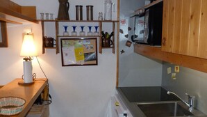 A compact kitchen with wooden shelves, a microwave, and a sink. - 2-room duplex, sleeps 6, ski-in/ski-out, Charmettoger (Les Arcs 1800)