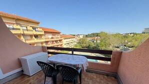 A balcony with a round table and chairs, a white heater, and a view of buildings and trees. - Spacious Apartment with Mezzanine and Parking, Near the Beach (Argelès-sur-Mer)