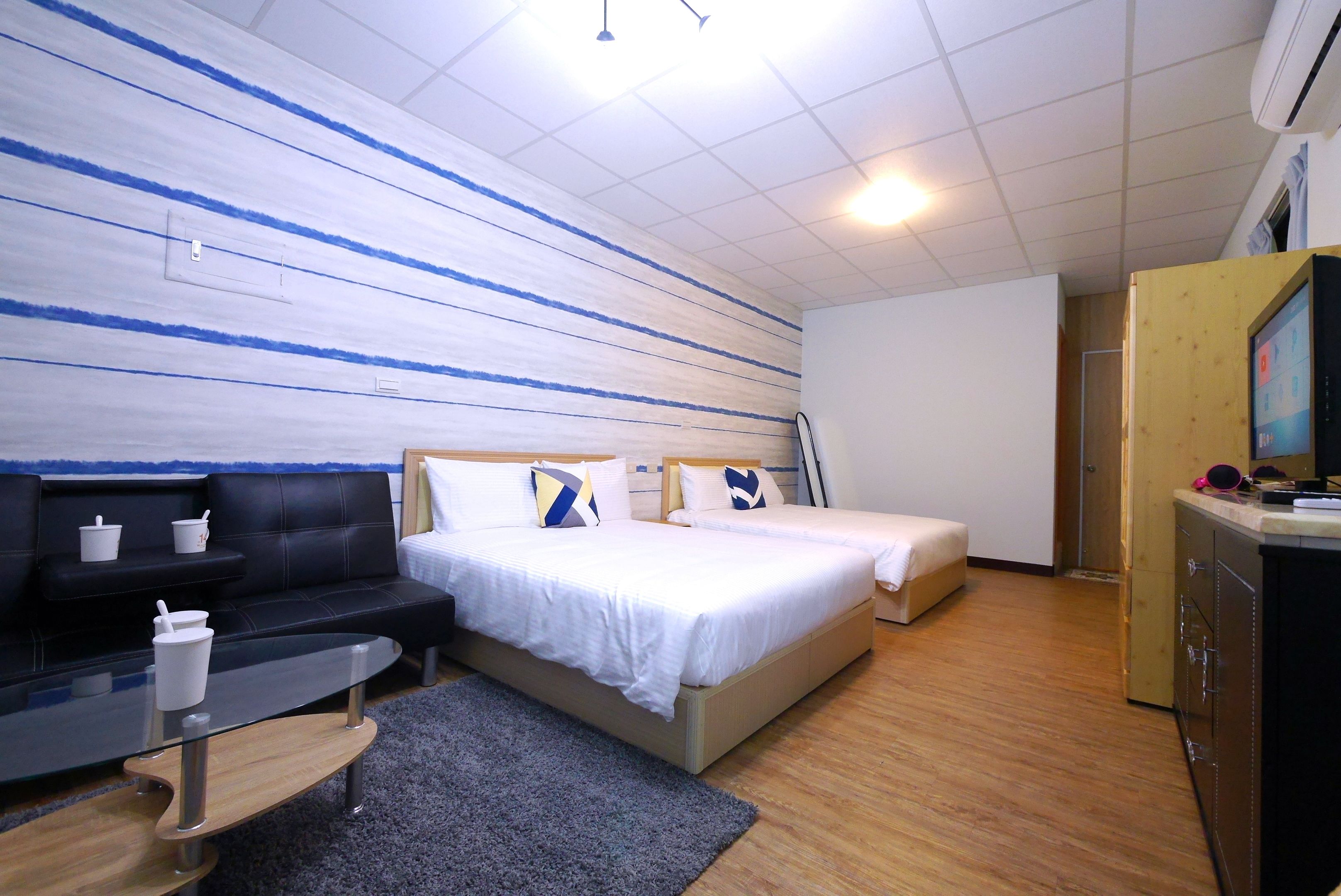A hotel room with a bed, a sofa, a small table, and a TV.