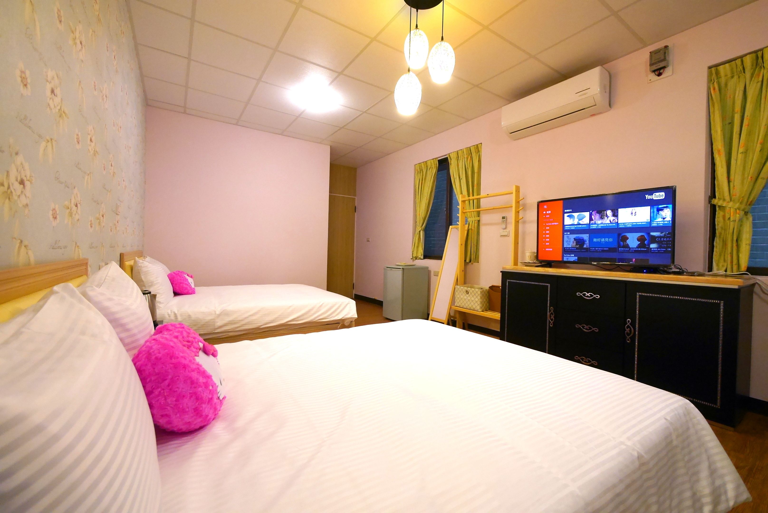 A hotel room with two beds, a television, and a desk.
