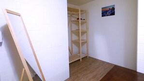 Una habitación con una estantería de madera frente a una pared de ladrillo blanco, un cuadro en la pared y suelo de madera.