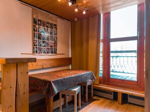 A cozy room with a wooden bench, a table with a patterned tablecloth, and a poster on the wall. - Cozy duplex studio for 3 in Arc 1800, near slopes and shops (Les Arcs 1800)
