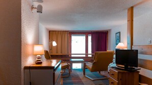 Une chambre d’hôtel équipée d’un lit, d’un bureau, d’une chaise, d’une télévision et d’une fenêtre avec des rideaux.