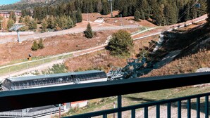 Un paysage montagneux avec un télésiège, un pont et un bâtiment au design moderne.