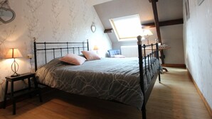 A bedroom with a sloped ceiling, a bed with a headboard, two bedside lamps, a radiator, and a window with natural light. - Rustic house in Vicq-sur-Mer - 6 people, Pets allowed (Vicq-sur-Mer)