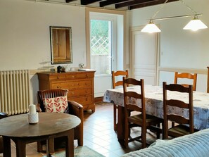 A cozy room with a wooden dresser, a round table, a bed with a floral bedspread, and two wooden chairs. - Rustic house in Vicq-sur-Mer - 6 people, Pets allowed (Vicq-sur-Mer)