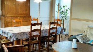 A dining area with a wooden table and chairs, a small round table with a candle, and a potted plant. - Rustic house in Vicq-sur-Mer - 6 people, Pets allowed (Vicq-sur-Mer)