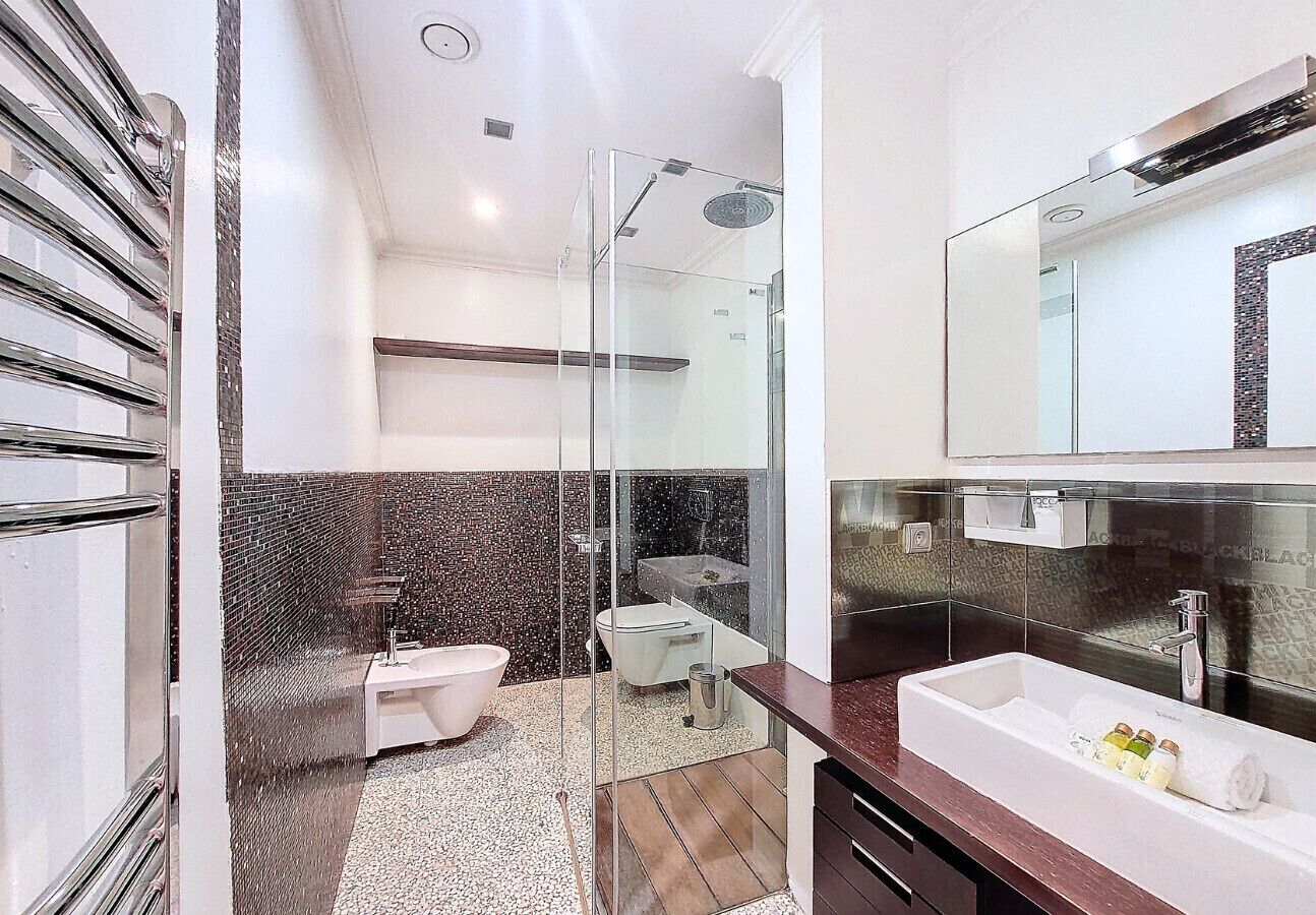 A modern bathroom with a glass-enclosed shower, a freestanding bathtub, a toilet, and a vanity with a large mirror.