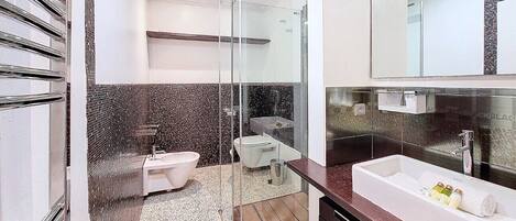 A modern bathroom with a glass-enclosed shower, a freestanding bathtub, a toilet, and a vanity with a large mirror.