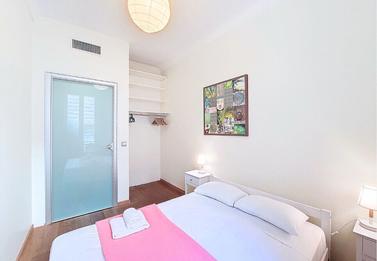 Una habitación de hotel con una cama, una mesita de noche con lámpara, una puerta y una obra de arte colgada en la pared.