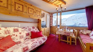 Een gezellige kamer met een houten bank, een eettafel en uitzicht op een besneeuwde berg.