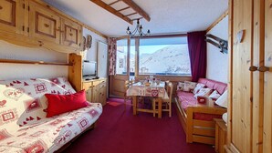 Een gezellige kamer met een bed, een eettafel en uitzicht op een besneeuwde berg.