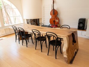 A dining area with a long wooden table, six chairs, a cello, a lamp, and a speaker. - Homerez - House near Montluçon (Montluçon)