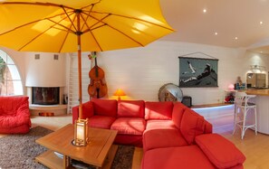 A living room with a red sofa, a wooden coffee table, a yellow umbrella, a fireplace, and a painting on the wall. - Homerez - House near Montluçon (Montluçon)