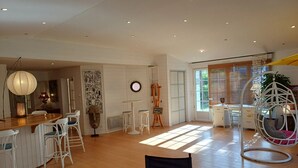 A spacious room with a wooden dining table, white chairs, a hanging chair, and a large window with blinds. - Homerez - House near Montluçon (Montluçon)