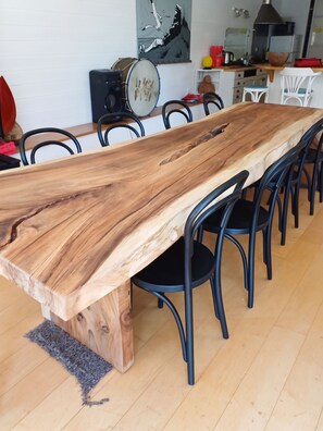A long wooden dining table with chairs, set in a room with a kitchen in the background. - Homerez - House near Montluçon (Montluçon)