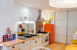 A compact kitchen with a sink, stove, and microwave. - Homerez - House near Montluçon (Montluçon)