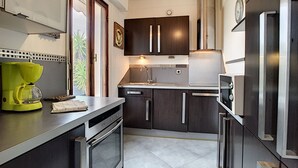 Una cocina moderna con armarios oscuros, electrodomésticos de acero inoxidable y una cafetera amarillo brillante.