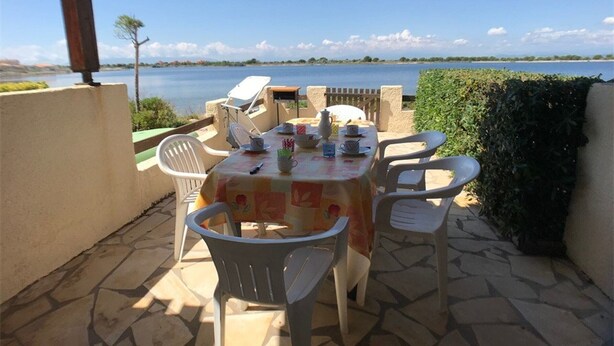 An outdoor patio with a table set for two, overlooking a body of water. - 3-Bedroom Villa + Mezzanine for 6 in Port Leucate with Parking (Port Leucate)