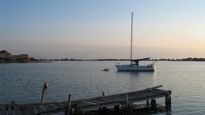 A calm body of water with a sailboat anchored near a wooden dock. - 3-Bedroom Villa + Mezzanine for 6 in Port Leucate with Parking (Port Leucate)