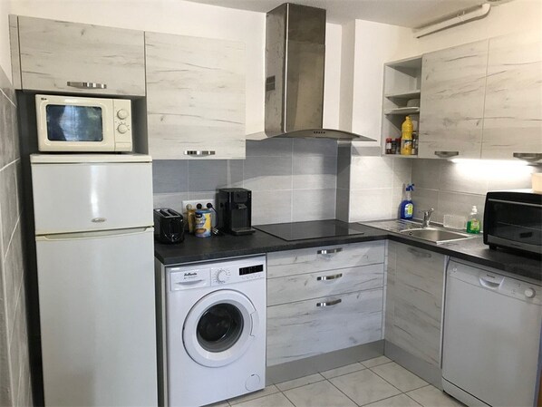 A compact kitchen with a microwave, toaster, coffee maker, and washing machine.
