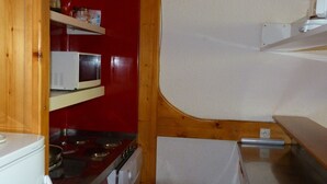 Kompakti keittiö, jossa on mikroaaltouuni, liesi ja pieni jääkaappi.