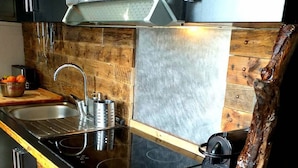 A kitchen with a wooden countertop, stainless steel appliances, and a unique wooden backsplash.