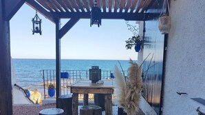 A wooden pergola with a table and chairs overlooking the sea.