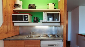 A compact kitchen with a microwave, toaster, and coffee maker on shelves, a sink, stove, and dishwasher below. - Ski-in/ski-out studio, balcony, pets allowed, Arc 1800 (Les Arcs 1800)